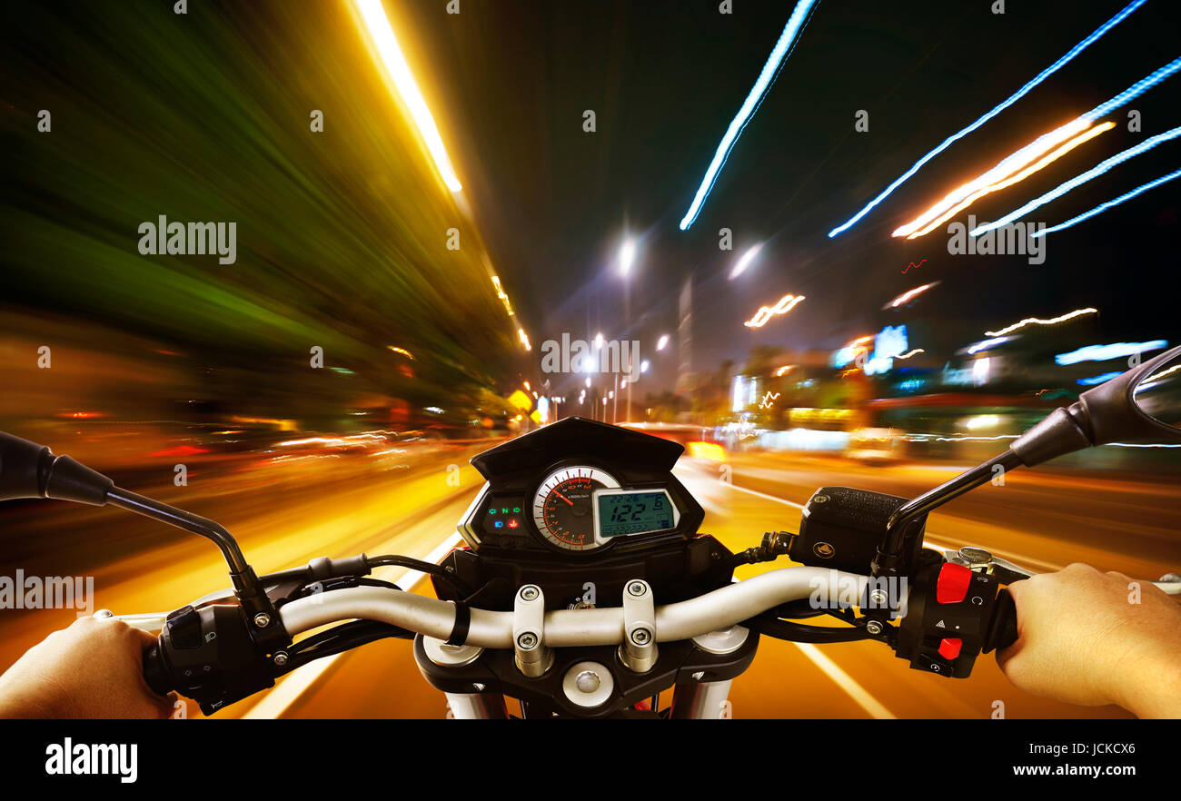 Biker driving a motorcycle rides along the city street , night scene