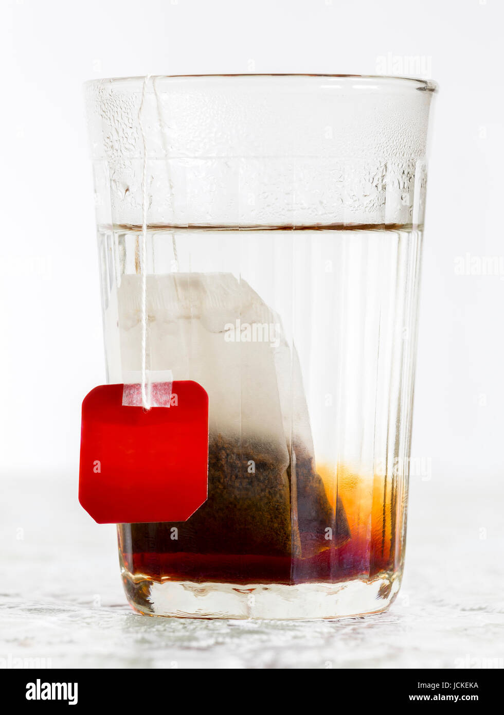 Faceted glass of boiled water and tea bag Stock Photo Alamy