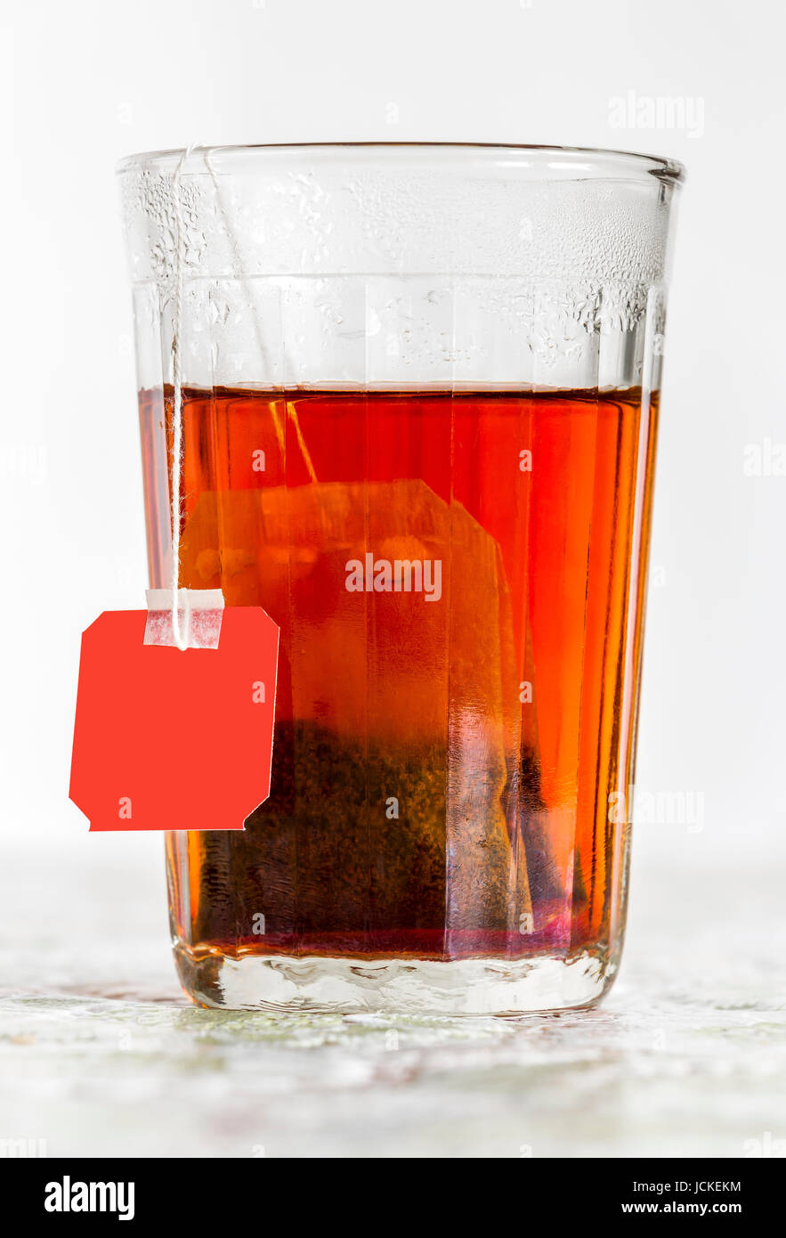 Faceted glass of boiled water and tea bag Stock Photo