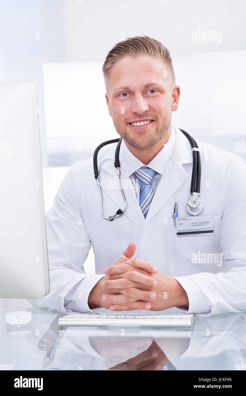 Smiling doctor or consultant sitting at a desk with his stethoscope