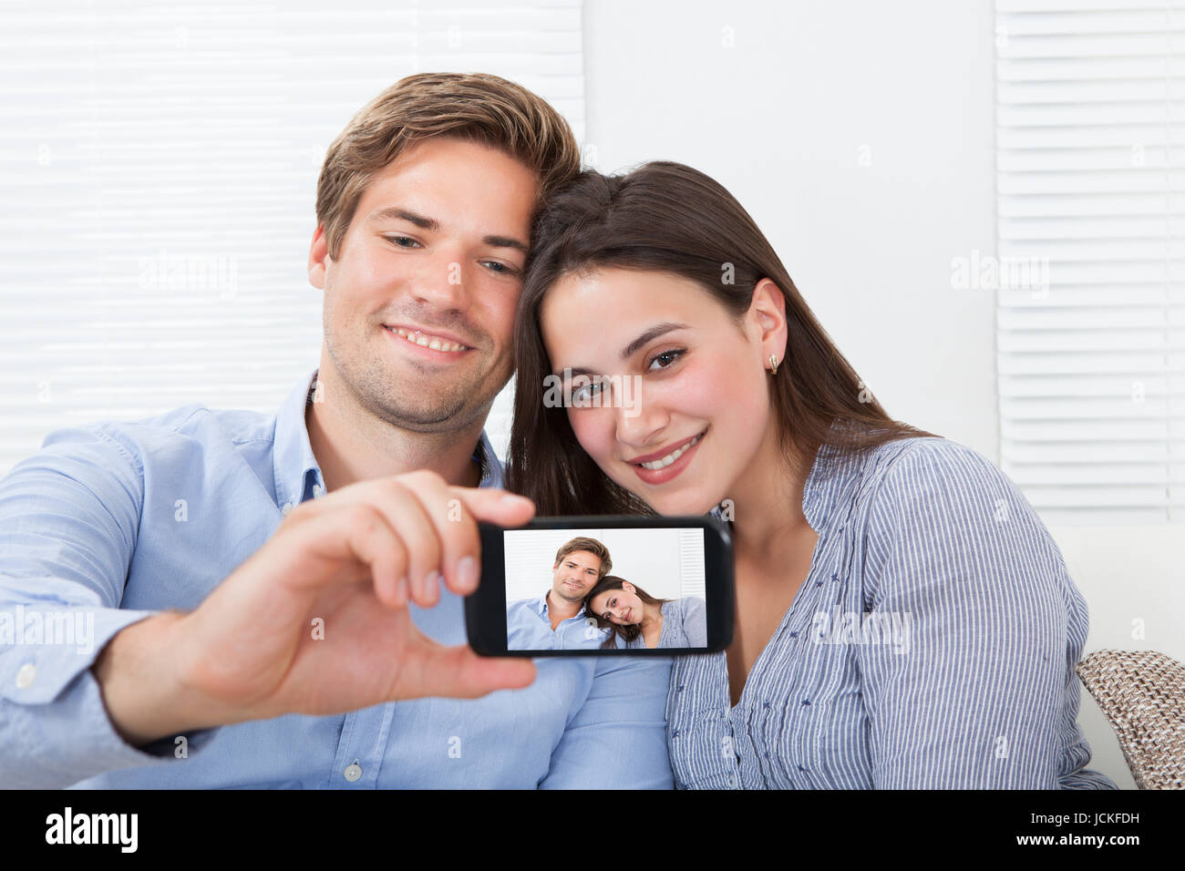 Happy couple taking self portrait through smartphone at home Stock ...