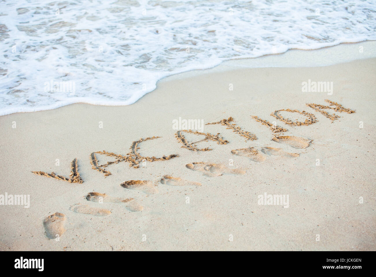 Word Vacation written in sand on beach Stock Photo - Alamy