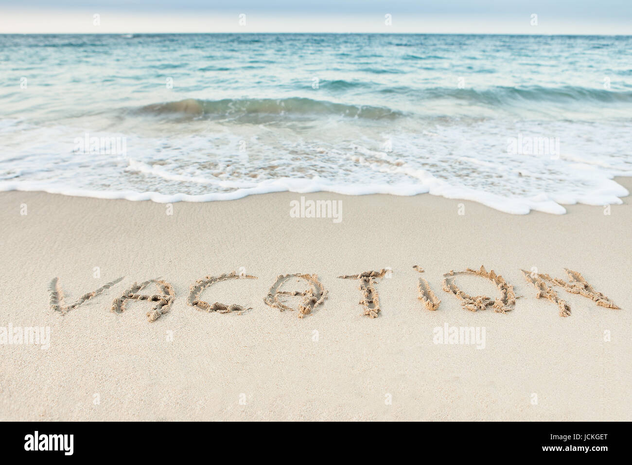 Word Vacation written in sand on beach Stock Photo - Alamy
