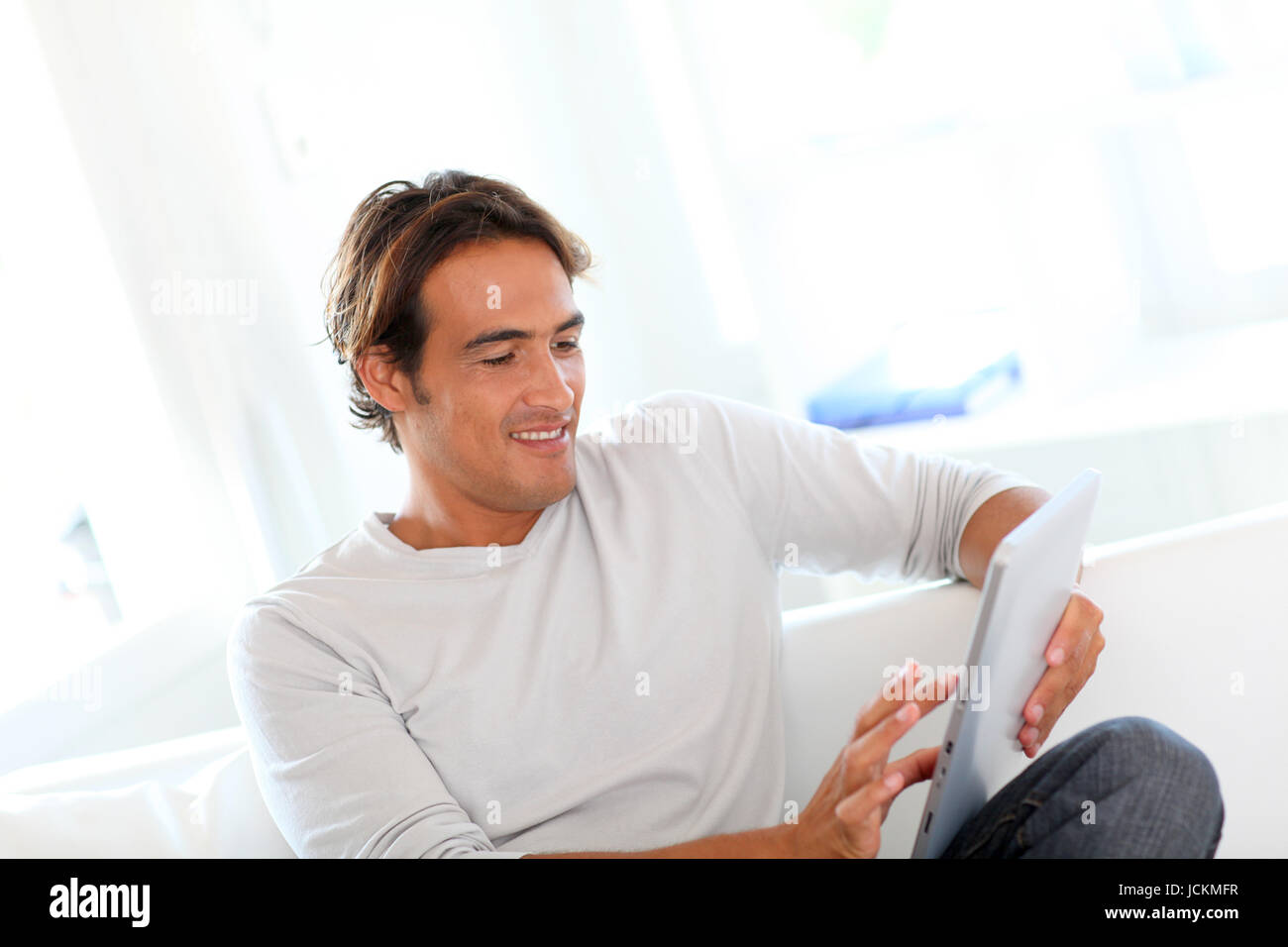Smiling man using touchpad at home Stock Photo