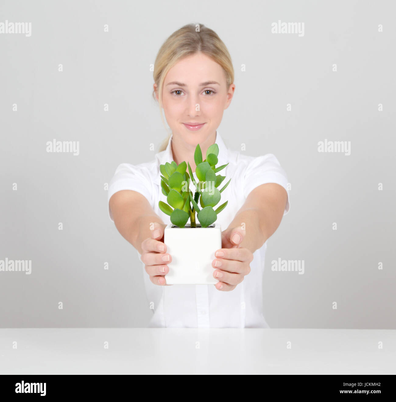 Beautiful blond woman holding plant pot Stock Photo - Alamy