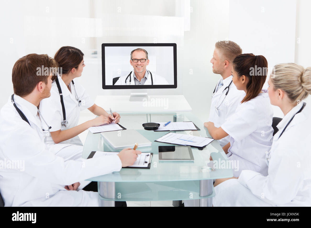 Team Of Doctors Attending Video Conference At Desk In Hospital Stock ...