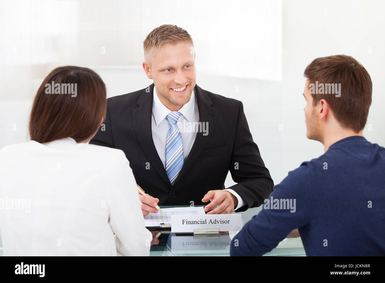 Rear View Of Young Couple Consulting Financial Advisor At Office