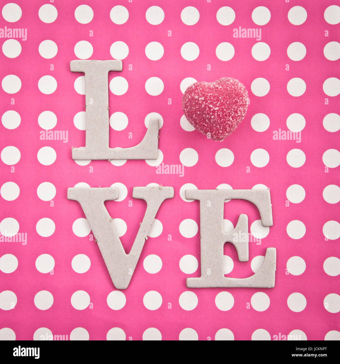 LOVE geschrieben mit rosa Praline auf pinkem Hintergrund Stock Photo