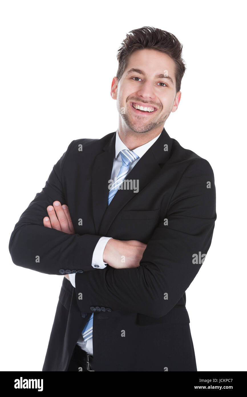 Portrait of smiling young businessman standing arms crossed over white ...