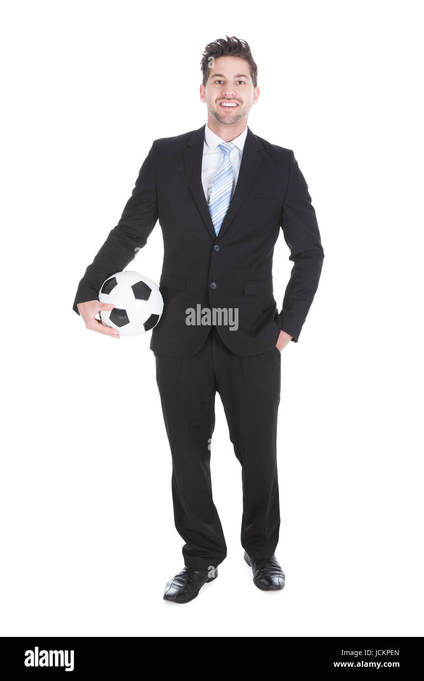 Full length portrait of confident young businessman holding soccer ball ...