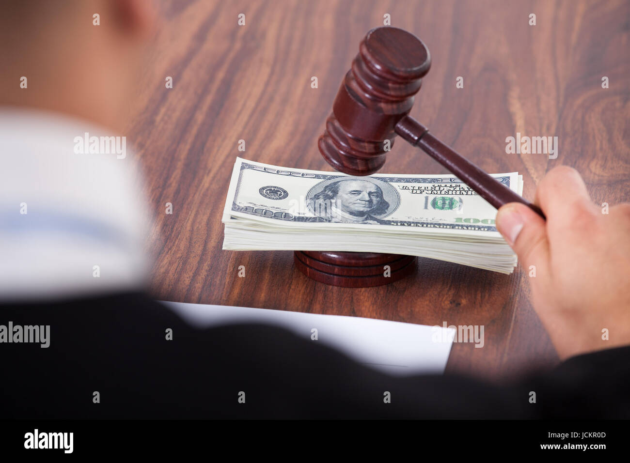 Cropped image of judge hitting mallet on banknotes in courtroom Stock Photo