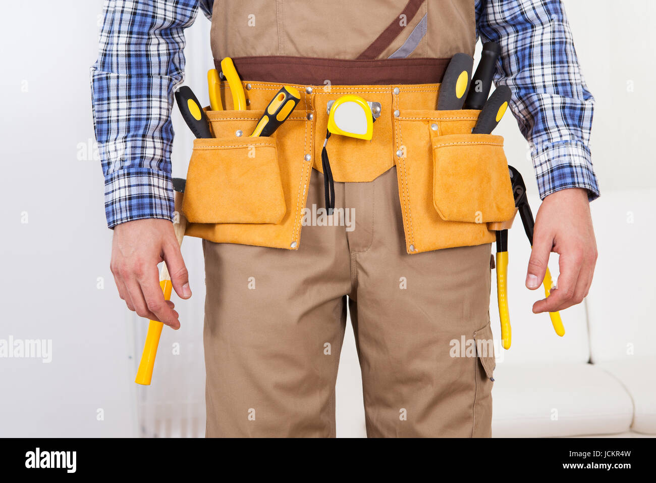 Midsection of young man wearing tool belt at home Stock Photo Alamy