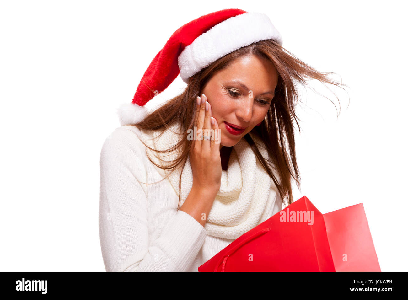 Attraktive junge Frau mit Nikolausmütze hält lachend eine rote Einkaufstasche Sale Schlussverkauf in der Hand auf weißem Hintergrund mit Textfreiraum Isoliert Freisteller Stock Photo