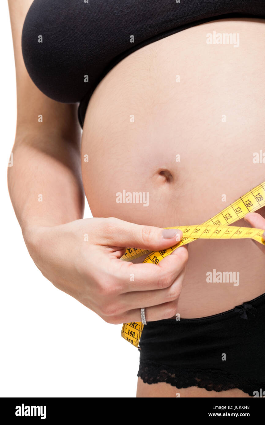 Schwangere Frau mit einem Maßband misst ihren Umfang am Bauch isoliert vor weißem Hintergrund Stock Photo
