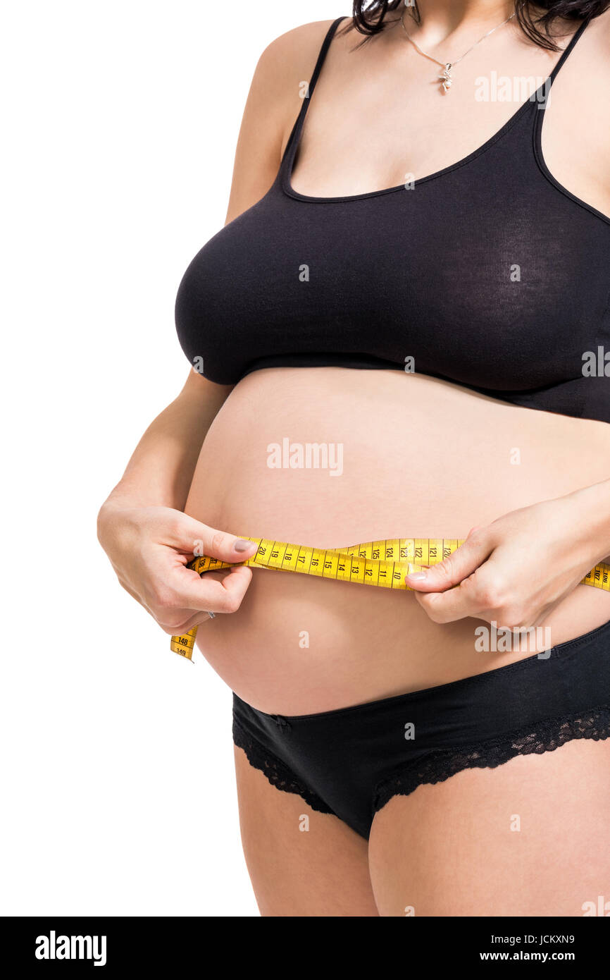 Schwangere Frau mit einem Maßband misst ihren Umfang am Bauch isoliert vor weißem Hintergrund Stock Photo