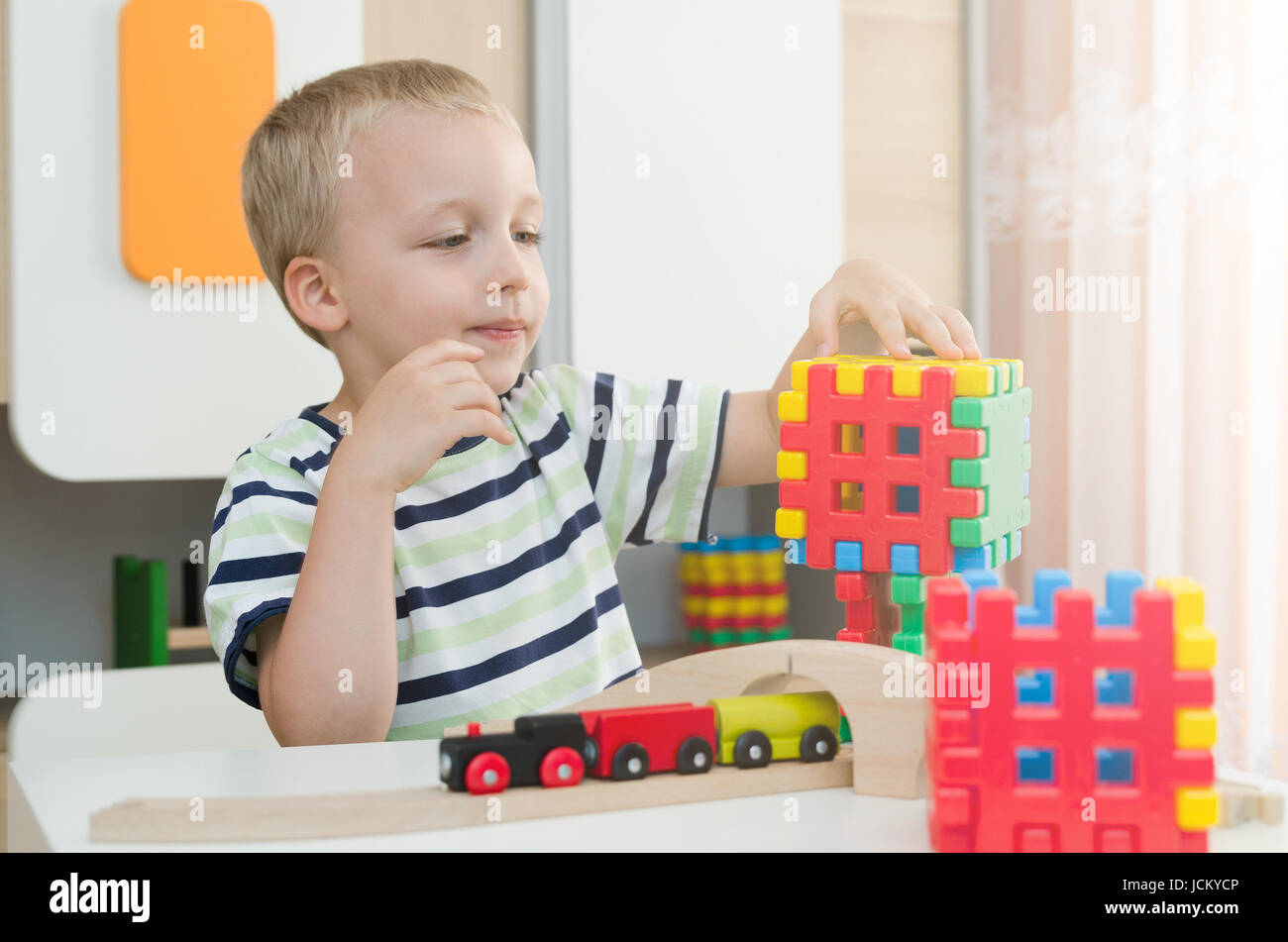 Little boy playing with blocks on a table. child kid young daycare boy playroom block build concept Stock Photo