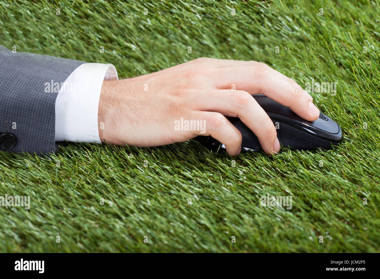 Closeup of businessman's hand using computer mouse on grass Stock Photo ...