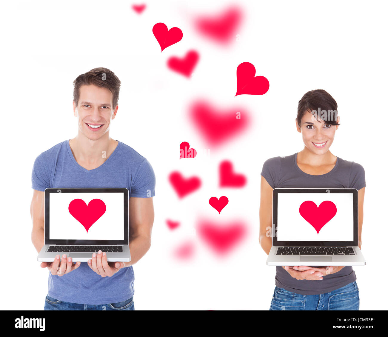 Portrait of young couple holding laptops with heart shape over white ...