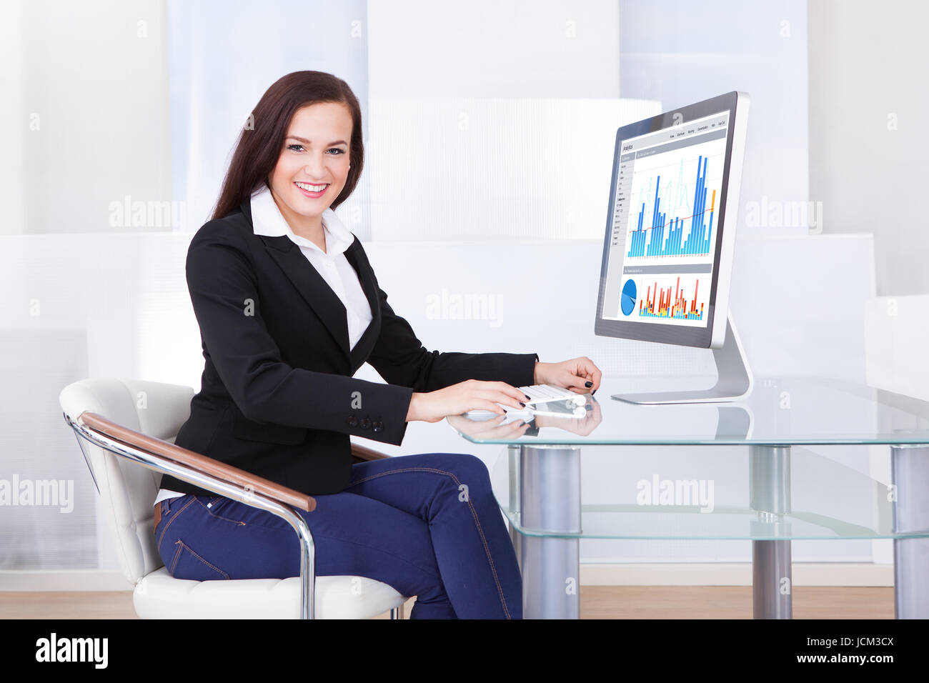 Young businesswoman using computer at desk in office Stock Photo - Alamy