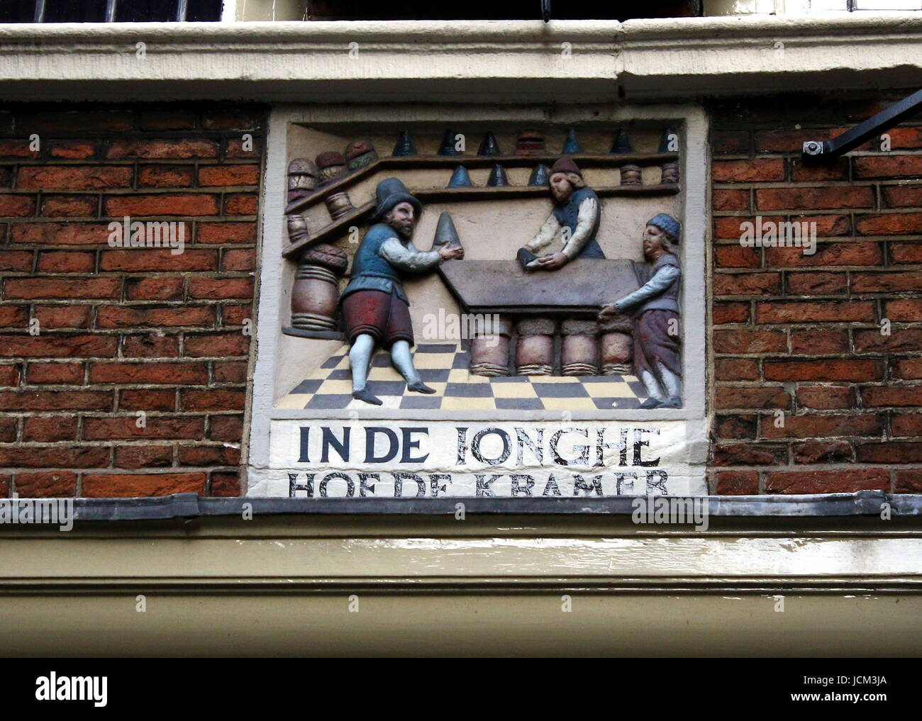 Old shop with 17th century gablestone 'In de Ionghe Hoede Kramer' (Young Hat Seller) at Warmoesstraat & Nieuwebrugsteeg, Amsterdam, Netherlands. Stock Photo