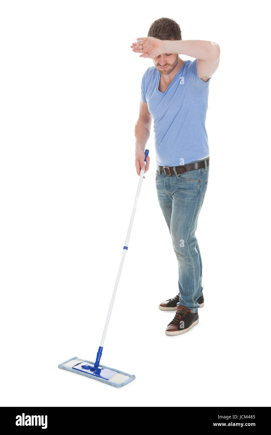 Full length of tired man mopping floor over white background Stock