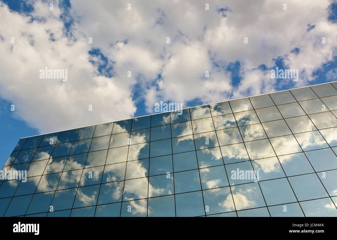 Glass facade of modern office building with reflection of blue sky and ...