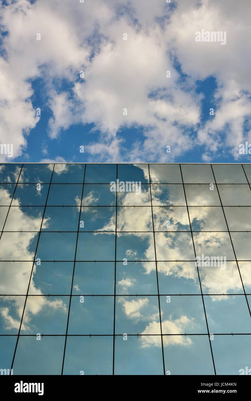 Glass facade of modern office building with reflection of blue sky and ...
