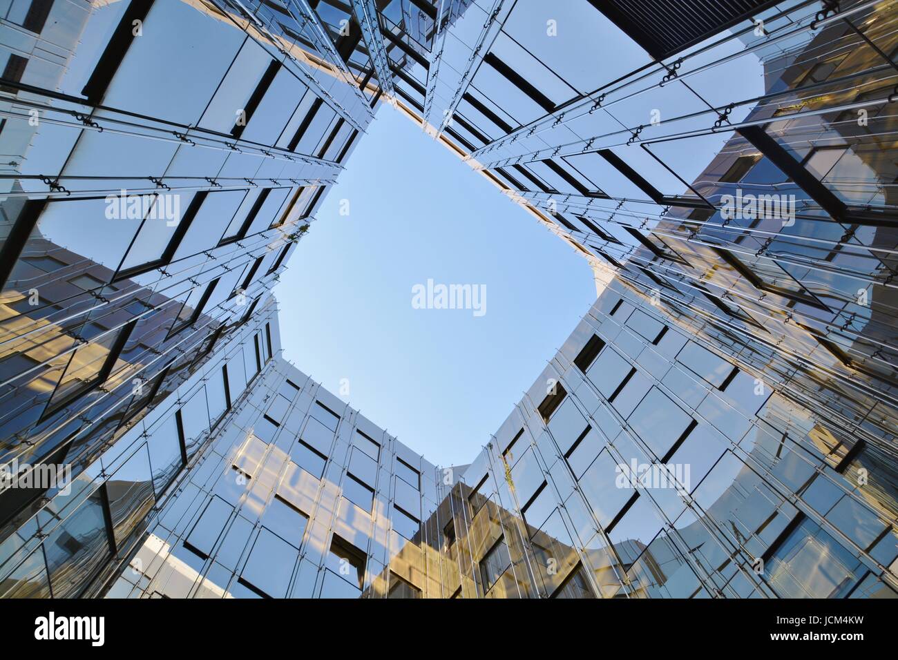 Glass facade of modern office building with reflection of blue sky and ...