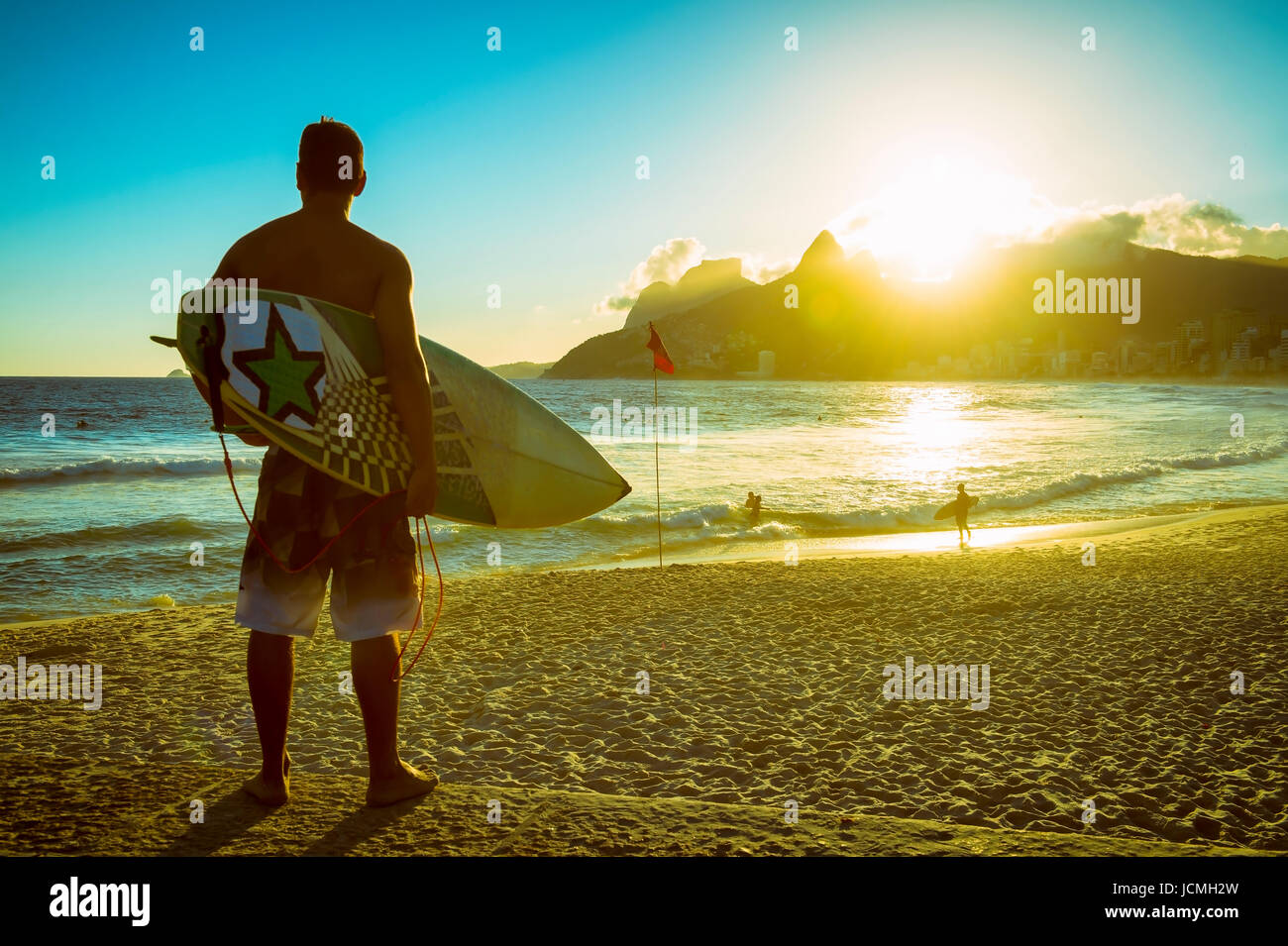 Sunset silhouette of surfer with his board wat at Arpching the sunset surf at Arpoador, Ipanema Beach, Rio de Janeiro, Brazil Stock Photo