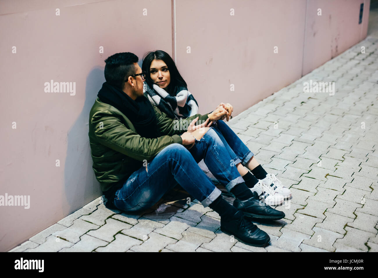 Young couple sitting outdoor on the ground chatting - interacting ...