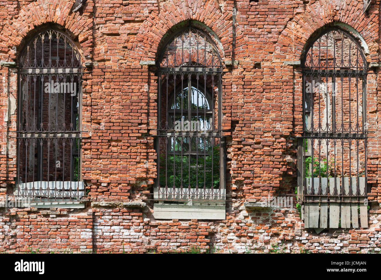 Collapsing red brick facade of an old abandoned church with empty windows Stock Photo