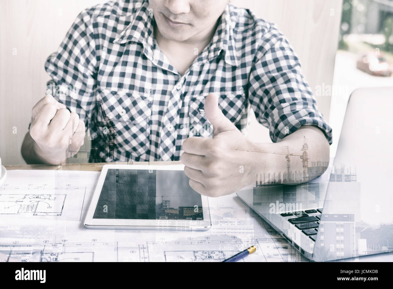 young male engineer worker raise his fist feeling happy and successful. Architect man show thumb up gesture with gladness after achieve construction p Stock Photo