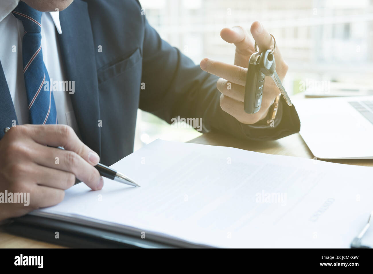 young businessman sign sales contract with car key at office. ownership, customer buying and salesman selling transportation concept. Stock Photo