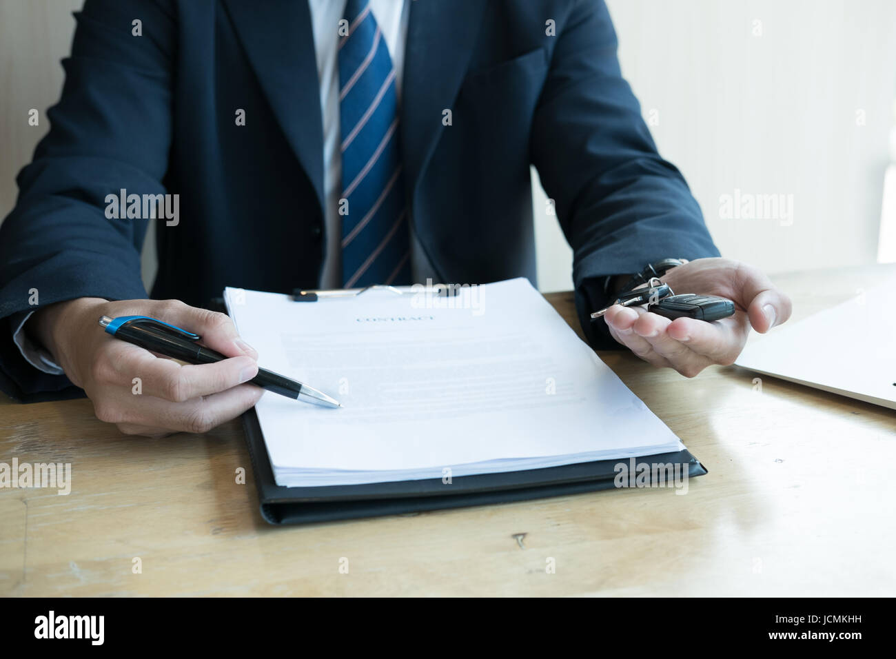 young businessman present signing sales contract with car key to customer at office. ownership, customer buying and salesman selling transportation co Stock Photo