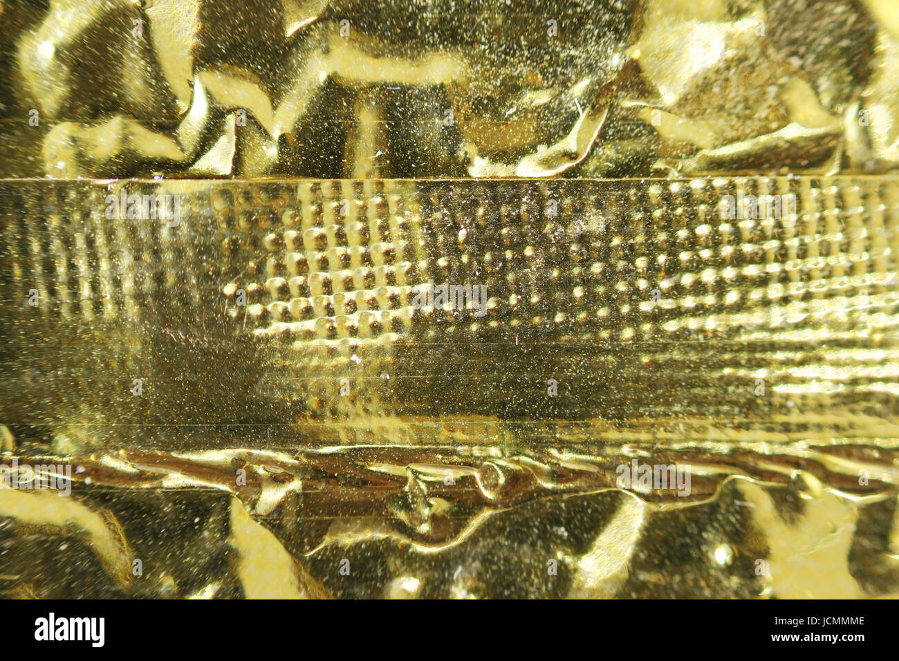 Macro photo of crumpled gold foil with seam from packaging of Chinese tea Stock Photo