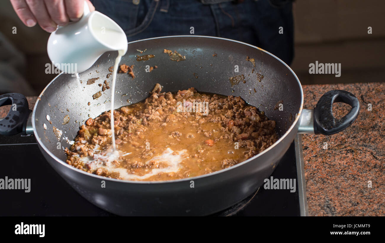 Cooking bolognese sauce for Italian pasta: pouring milk Stock Photo