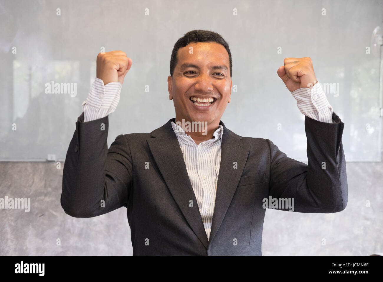 Successful asian businessman gesturing with happiness and gladness at office. Start up entrepreneur enjoys success in job at workplace. business achie Stock Photo