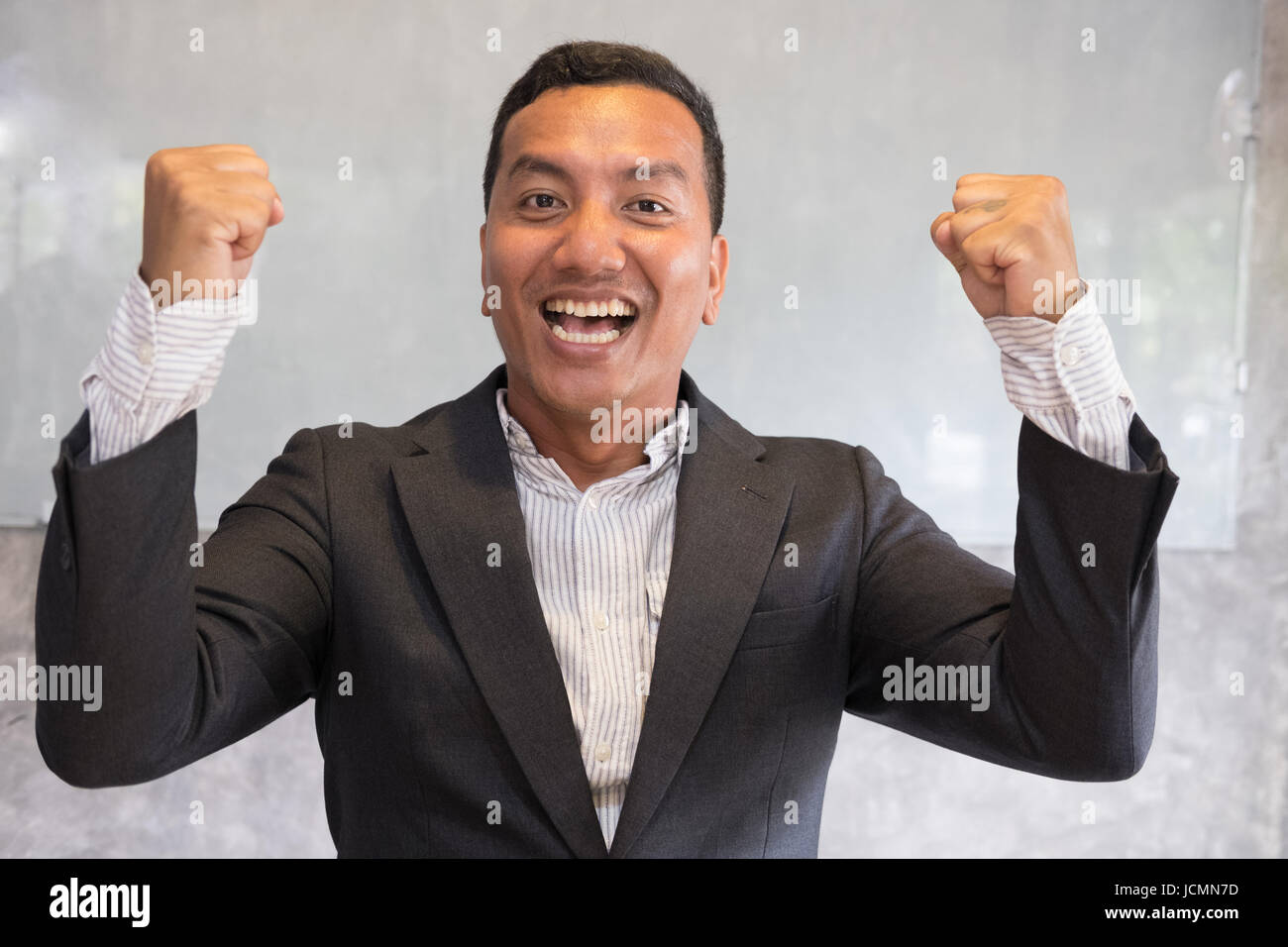 Successful asian businessman gesturing with happiness and gladness at office. Start up entrepreneur enjoys success in job at workplace. business achie Stock Photo