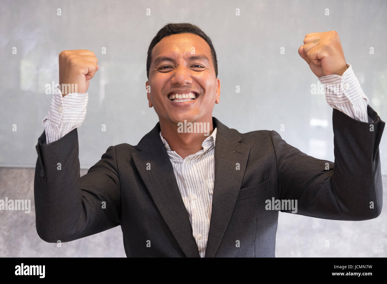 Successful asian businessman gesturing with happiness and gladness at office. Start up entrepreneur enjoys success in job at workplace. business achie Stock Photo