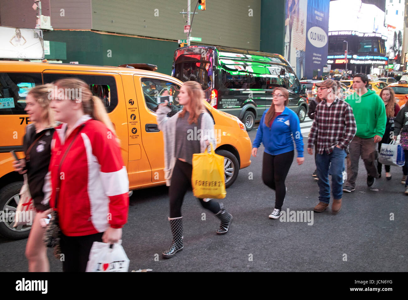 people walking in the road through stopped traffic evening in Times Square New York City USA deliberate motion blur Stock Photo