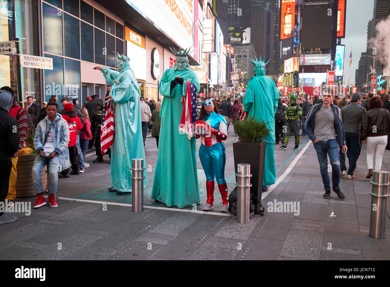 costumed characters including superheroes and statues of liberty in boxed off zone on Times Square New York City USA Stock Photo