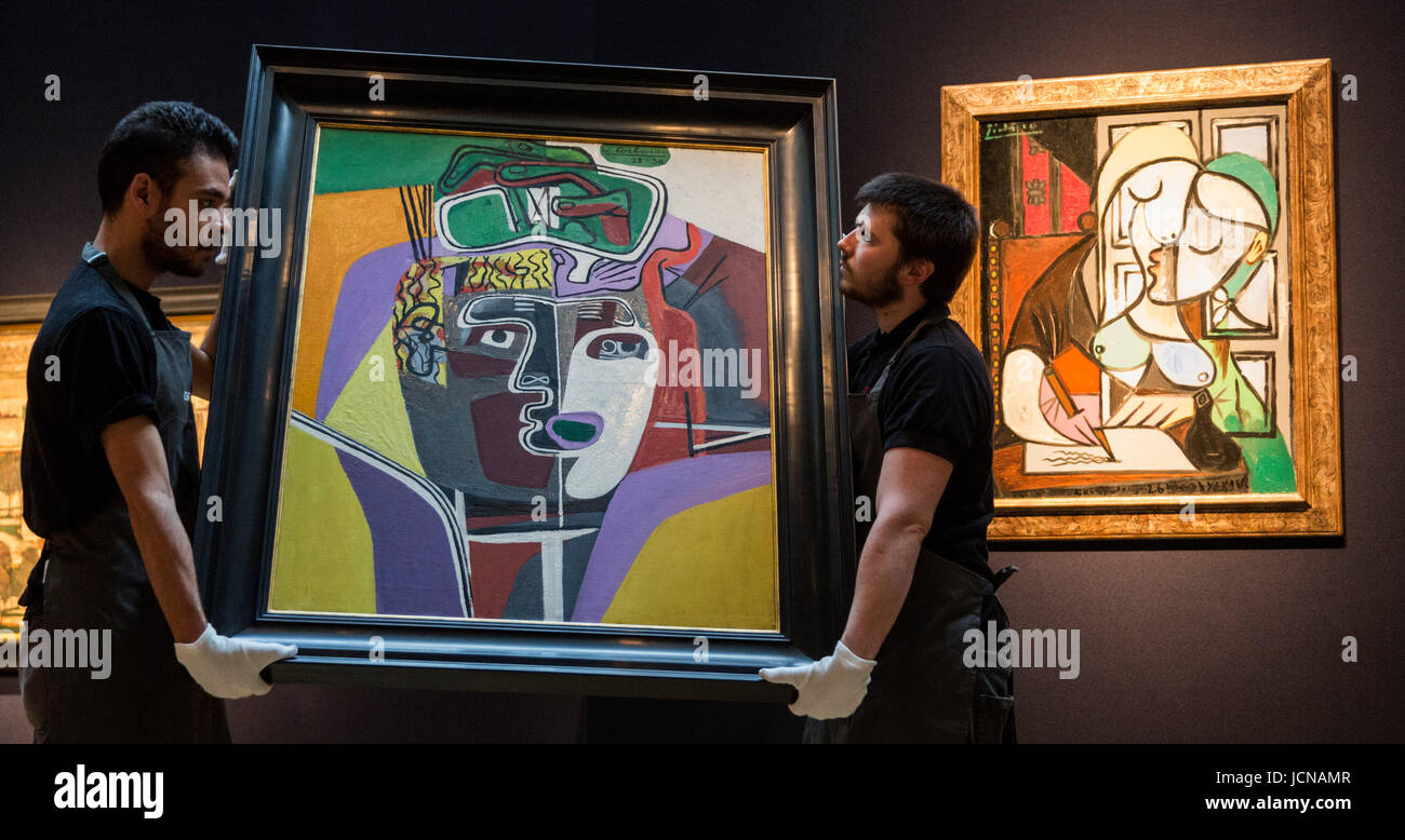 London, UK. 16 June 2017. Christie's technicians handling the painting Mains croisees sur la tete, 1939-40, by Le Corbusier, est GBP 1.2-2m which is influenced by Pablo Picasso. At the back the Pablo Picasso painting Femme ecrivant (Marie-Therese), 1934, est GBP 25-40m. Auction house Christie's presents a preview of the Impressionist and Modern Art evening sale on 27 June 2017. The sale is part of 20th Century at Christie's and is led by a group of masterpiece paintings by Max Beckmann, Claude Monet, Pablo Picasso, Egon Schiele and Vincent van Gogh. Stock Photo