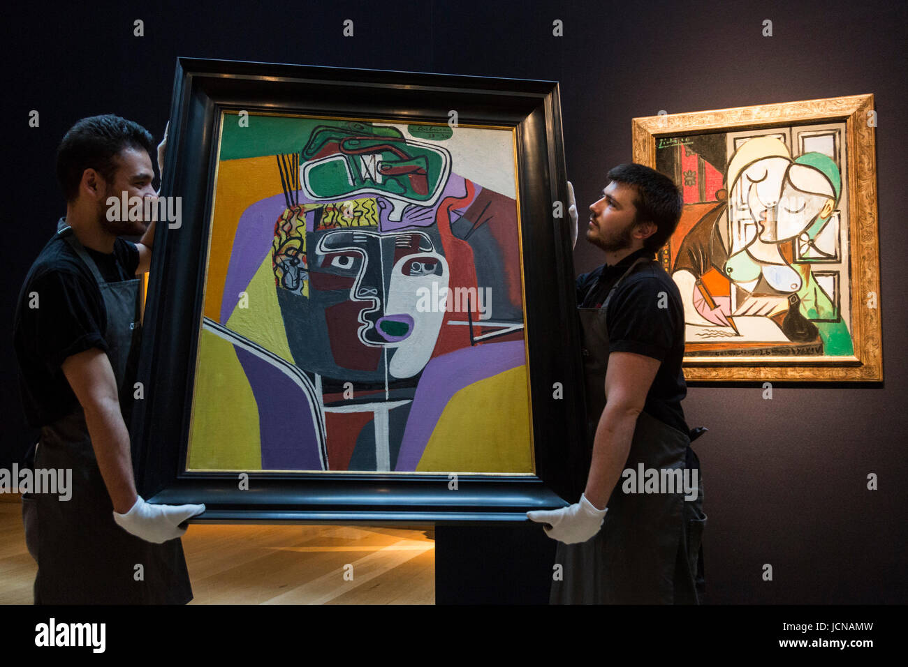 London, UK. 16 June 2017. Christie's technicians handling the painting Mains croisees sur la tete, 1939-40, by Le Corbusier, est GBP 1.2-2m which is influenced by Pablo Picasso. At the back the Pablo Picasso painting Femme ecrivant (Marie-Therese), 1934, est GBP 25-40m. Auction house Christie's presents a preview of the Impressionist and Modern Art evening sale on 27 June 2017. The sale is part of 20th Century at Christie's and is led by a group of masterpiece paintings by Max Beckmann, Claude Monet, Pablo Picasso, Egon Schiele and Vincent van Gogh. Stock Photo