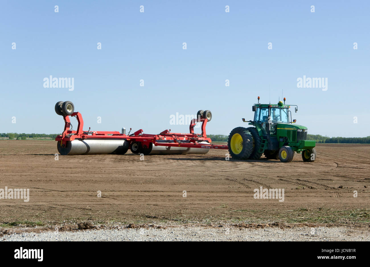 John Deere tractor with Rite Way 3 section land roller in prepared farm field Stock Photo