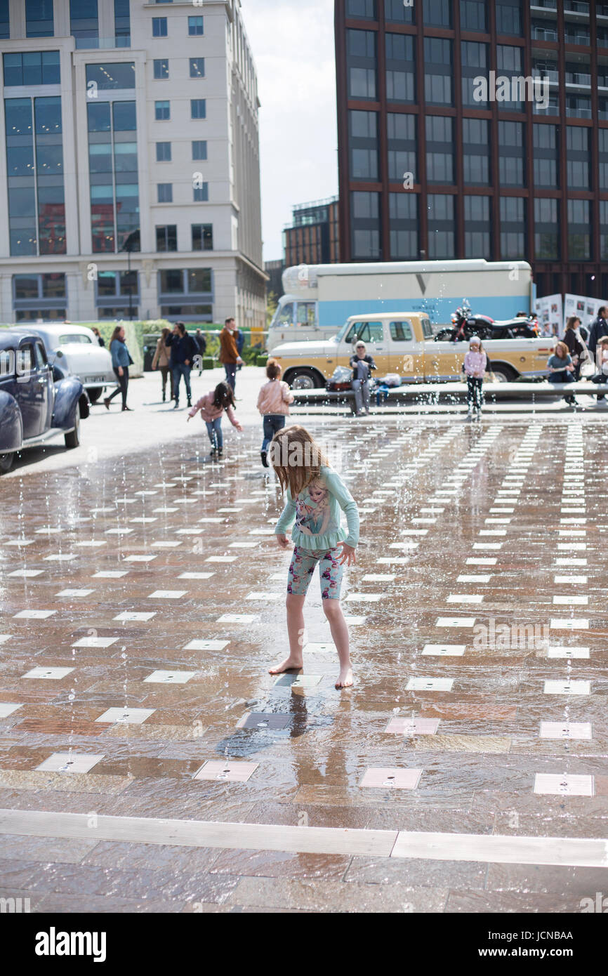Girl plays in water fountain. Stock Photo