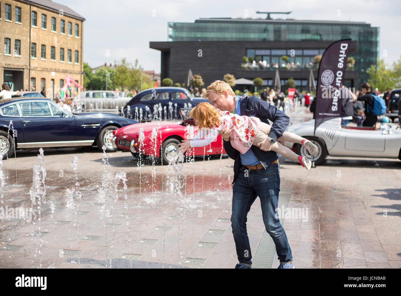 Dad plays with daughter in fountain in London. Stock Photo