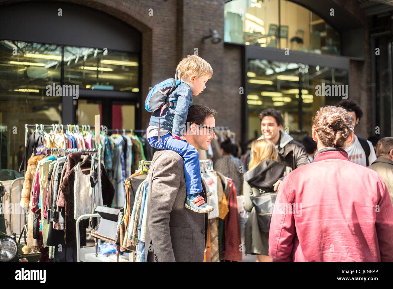 Father carries son on shoulder through a vintage London market. Stock Photo