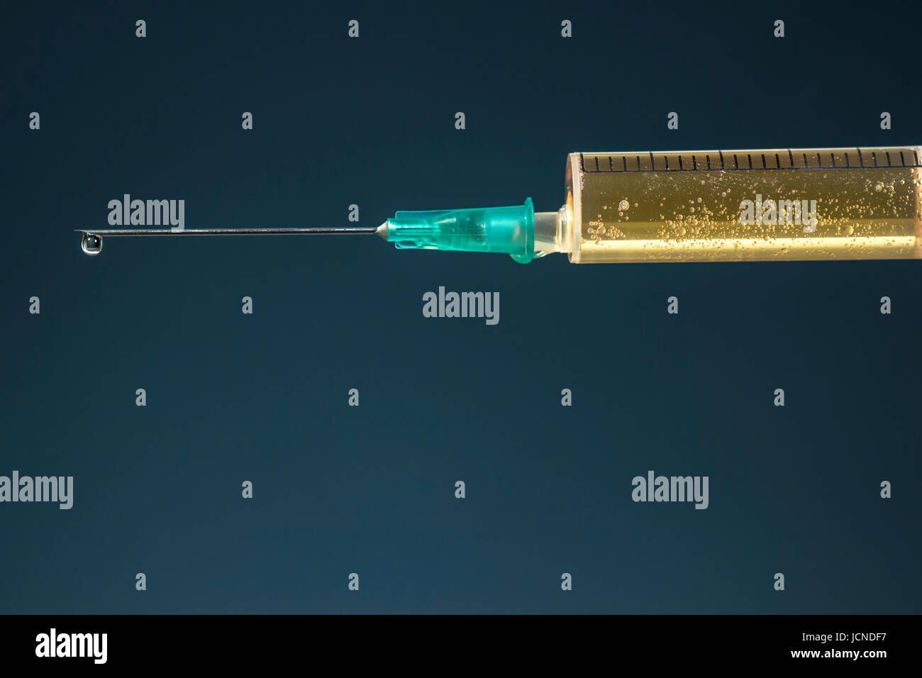 Hypodermic needle with a drop at its tip and syringe with dark yellow