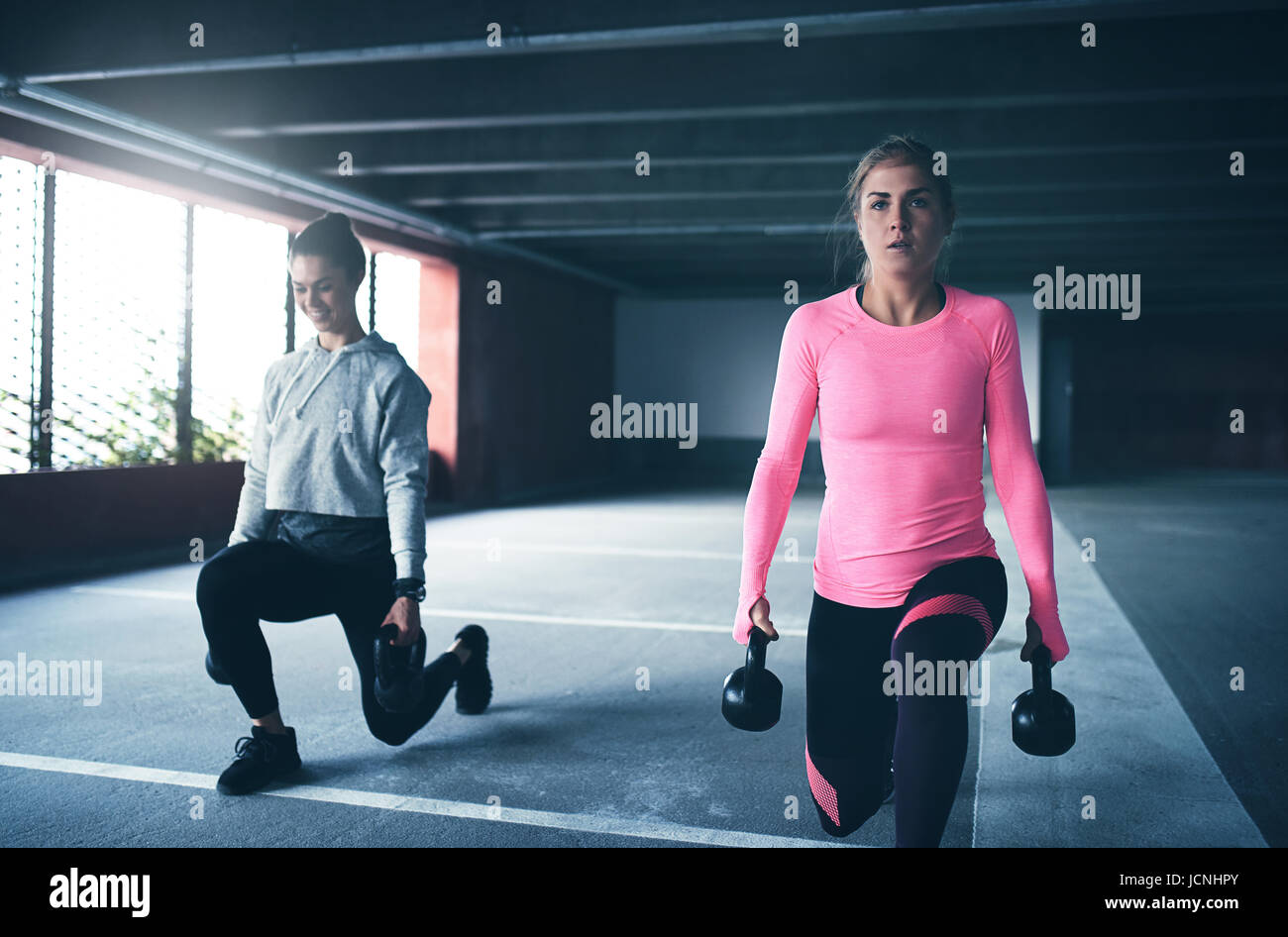 Young pretty women in sportswear training with dumb bell at sports ground. Stock Photo