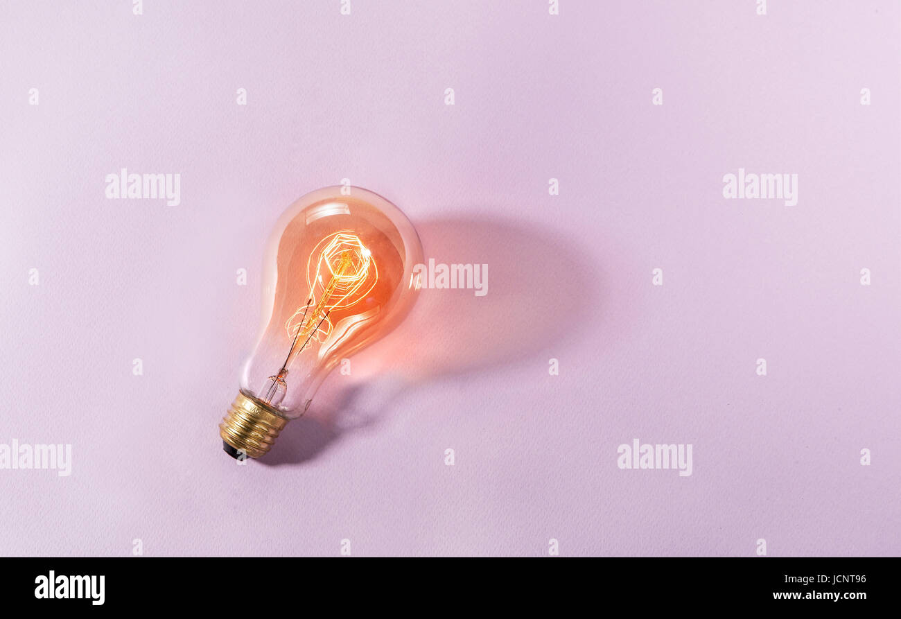 Lightbulb illuminated on colored sheet. Top view Stock Photo